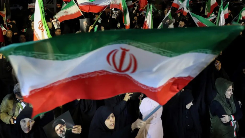 image of Iranian flag being waved above a group of protesters